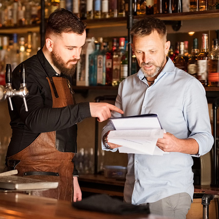 Regional manager and restaurant manager looking over notes in bar